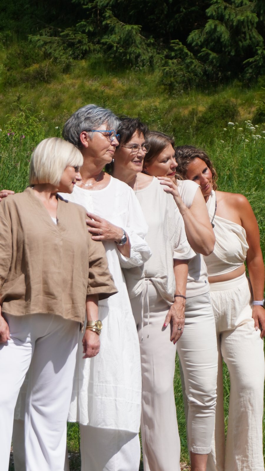 Fünf Frauen stehen Arm in Arm auf einer Wiese