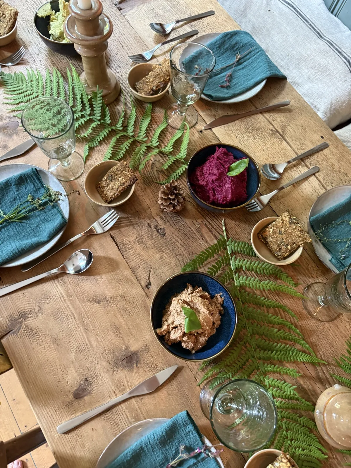 Gedeckter Holztisch mit Schalen, Farn und Gläsern von oben