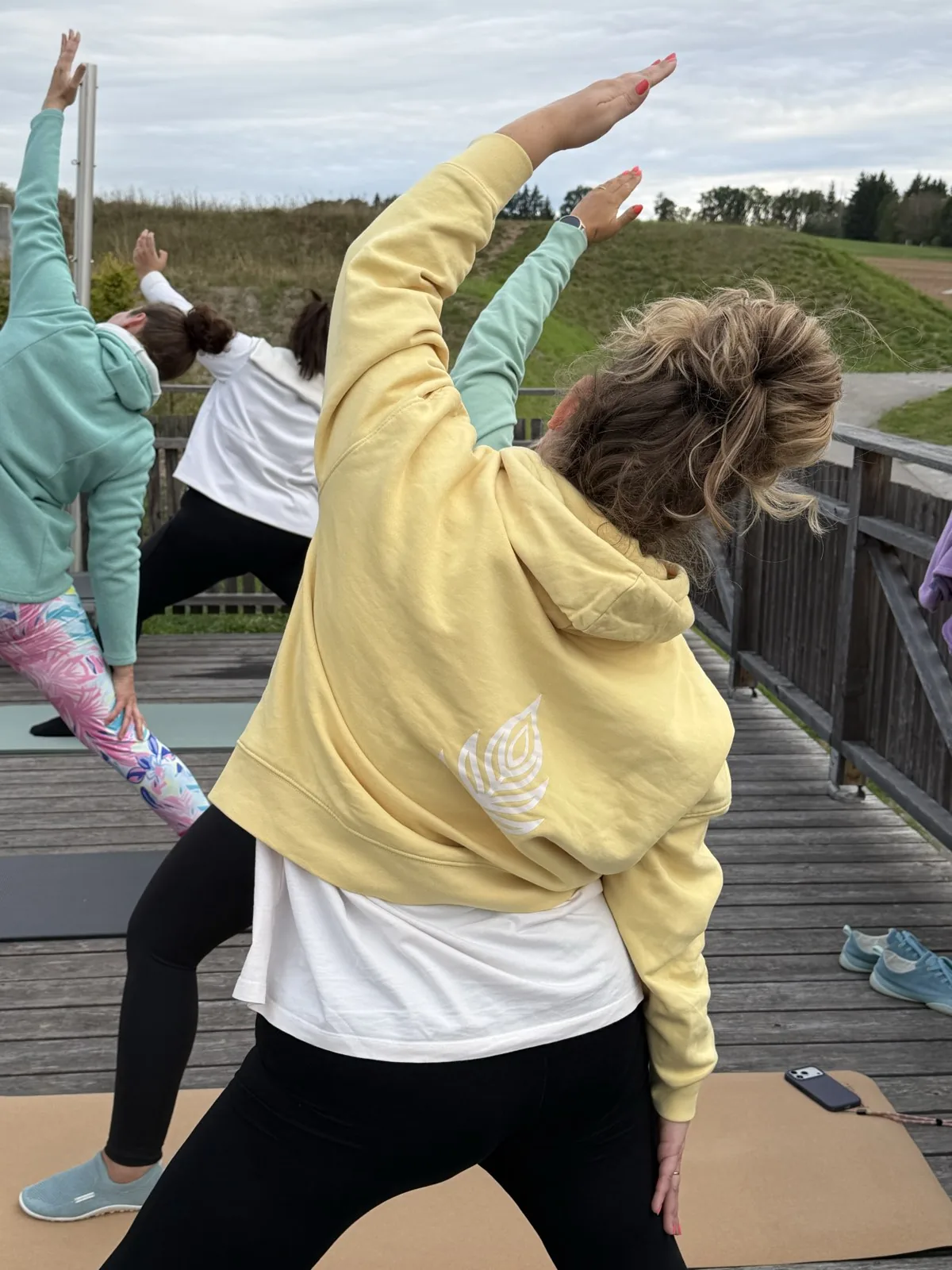 Frauen in P7-Hoodies beim Yoga auf einer Holzterrasse